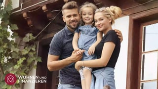 Glückliche Familie mit Kind vor Eigenheim